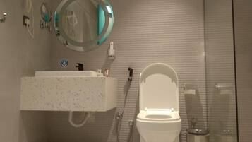 Un baño con inodoro, lavabo, espejo y ducha.