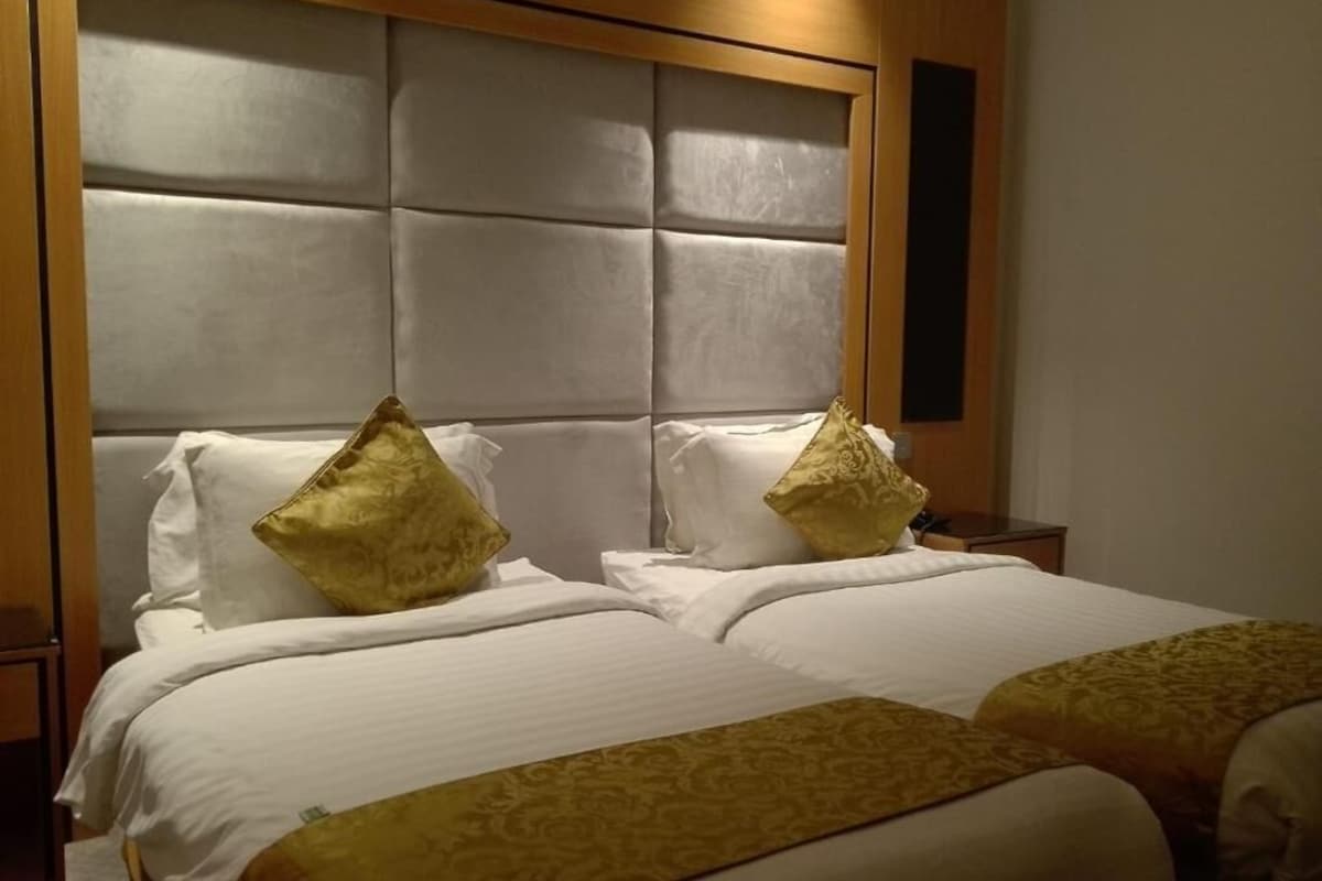 A hotel room with a large bed, two pillows, and a headboard.