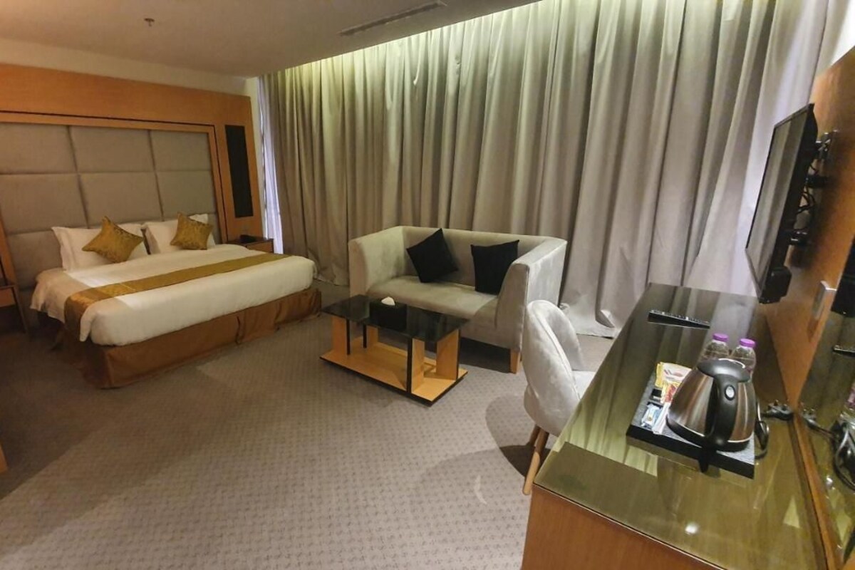 A hotel room with a bed, a sofa, a small table, and a TV.