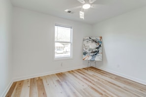 A room with hardwood flooring, a ceiling fan, a window with blinds, and a large abstract painting on the wall. - 3-bedroom house in beautiful Sumter with cool AC breeze (Sumter)