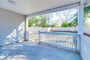 A covered porch with a white railing, a concrete floor, and a view of a backyard with a wooden fence and trees. - 3-bedroom house in beautiful Sumter with cool AC breeze (Sumter)