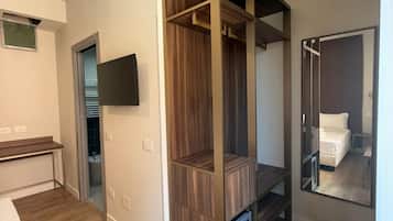 A modern bedroom with a wooden wardrobe, a flat-screen TV, and a large mirror reflecting the room.