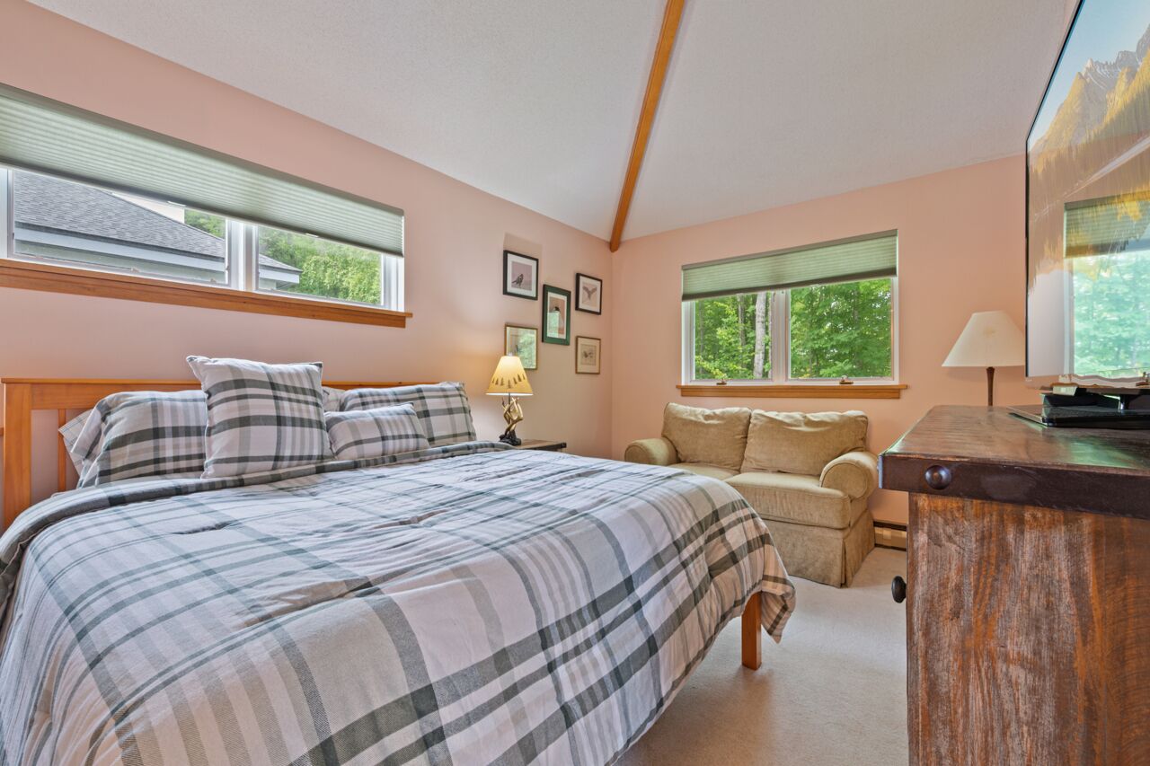 Ett sovrum med en stor säng, en soffa, ett skrivbord och två fönster.