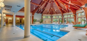 Una piscina interior amb sostre de fusta i grans finestres.