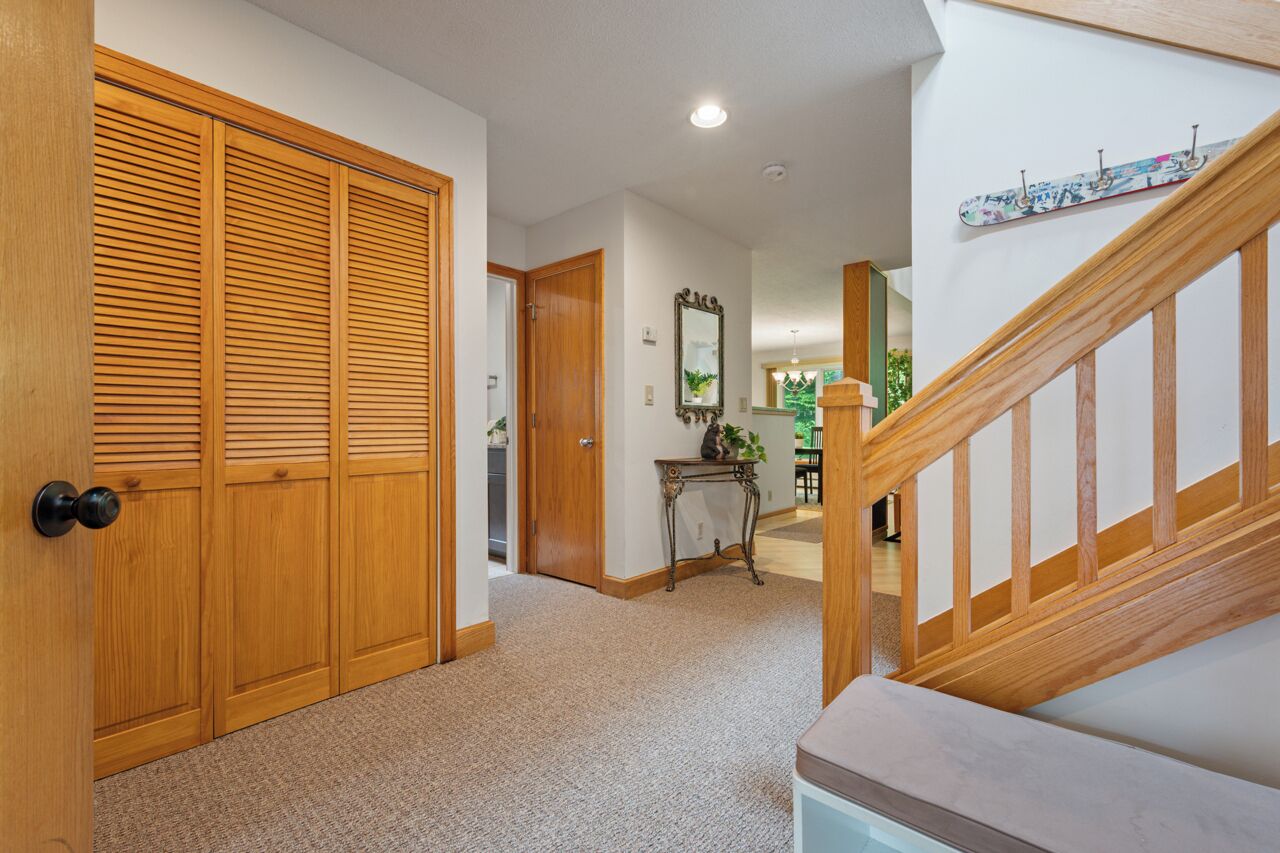 A hallway with a wooden door, a staircase, and a mirror on the wall.