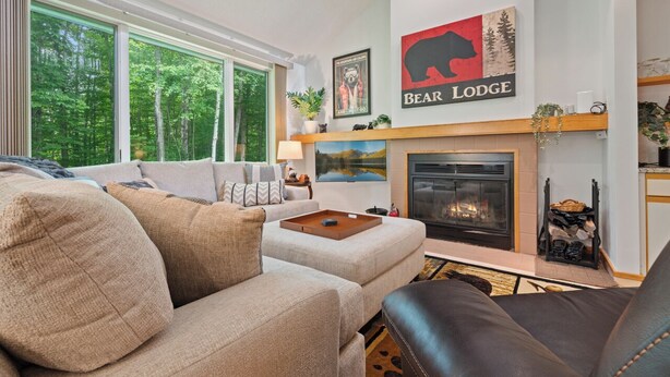 A cozy living room with a fireplace, a sofa, and a coffee table. - The Woods Killington - 2B with Spa, Pool & Jacuzzi (Killington)