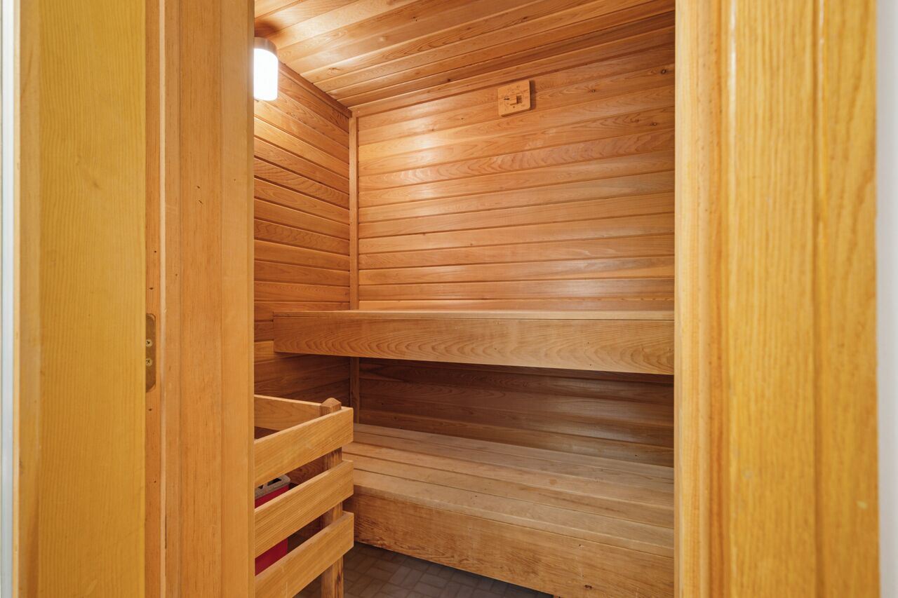 A wooden sauna with a slatted ceiling and a bench.