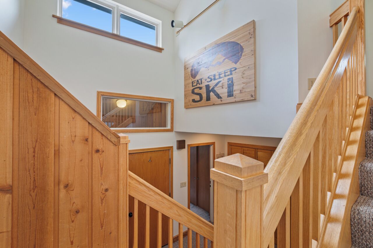A wooden staircase with a sign that reads 'EAT SLEEP SKI' on the wall.
