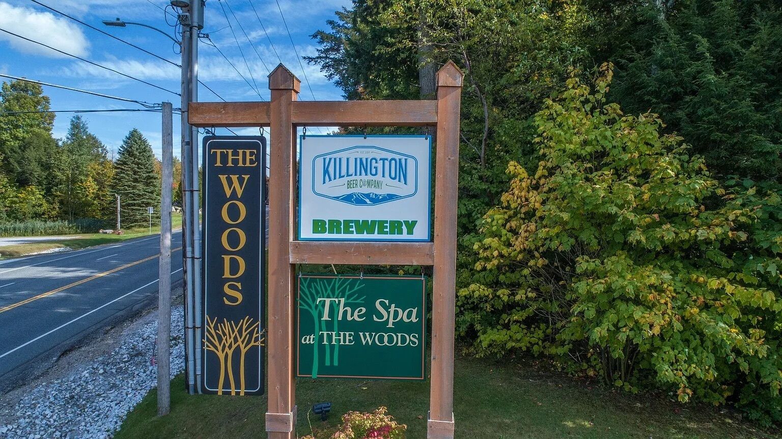 A signboard with multiple business names including 'The Woods,' 'Killington Brewery,' and 'The Spa at The Woods.'