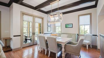 A dining area with a white table, four chairs, and a chandelier.