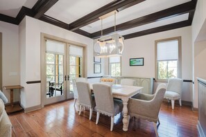 Un comedor con una mesa blanca, cuatro sillas y una araña.