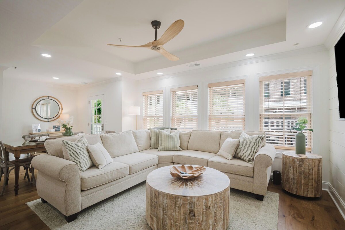 A modern living room with a sectional sofa, round coffee table, and a ceiling fan.
