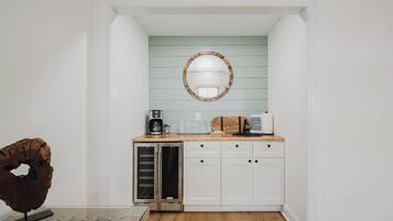 A compact kitchen with a built-in refrigerator, a coffee maker, and a microwave on the countertop.