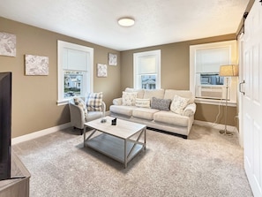 A living room with a beige sofa, a coffee table, and a TV on a stand. - Cedar Point in 10 Min  Cozy 2BR (Sandusky)