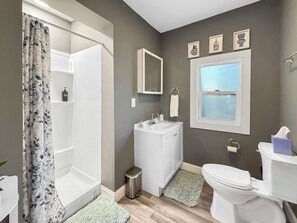 Ein Badezimmer mit Dusche, Waschbecken, Toilette und einem Fenster.