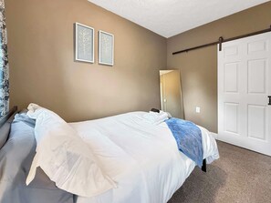 Quarto com cama, mesa de cabeceira, espelho e porta.