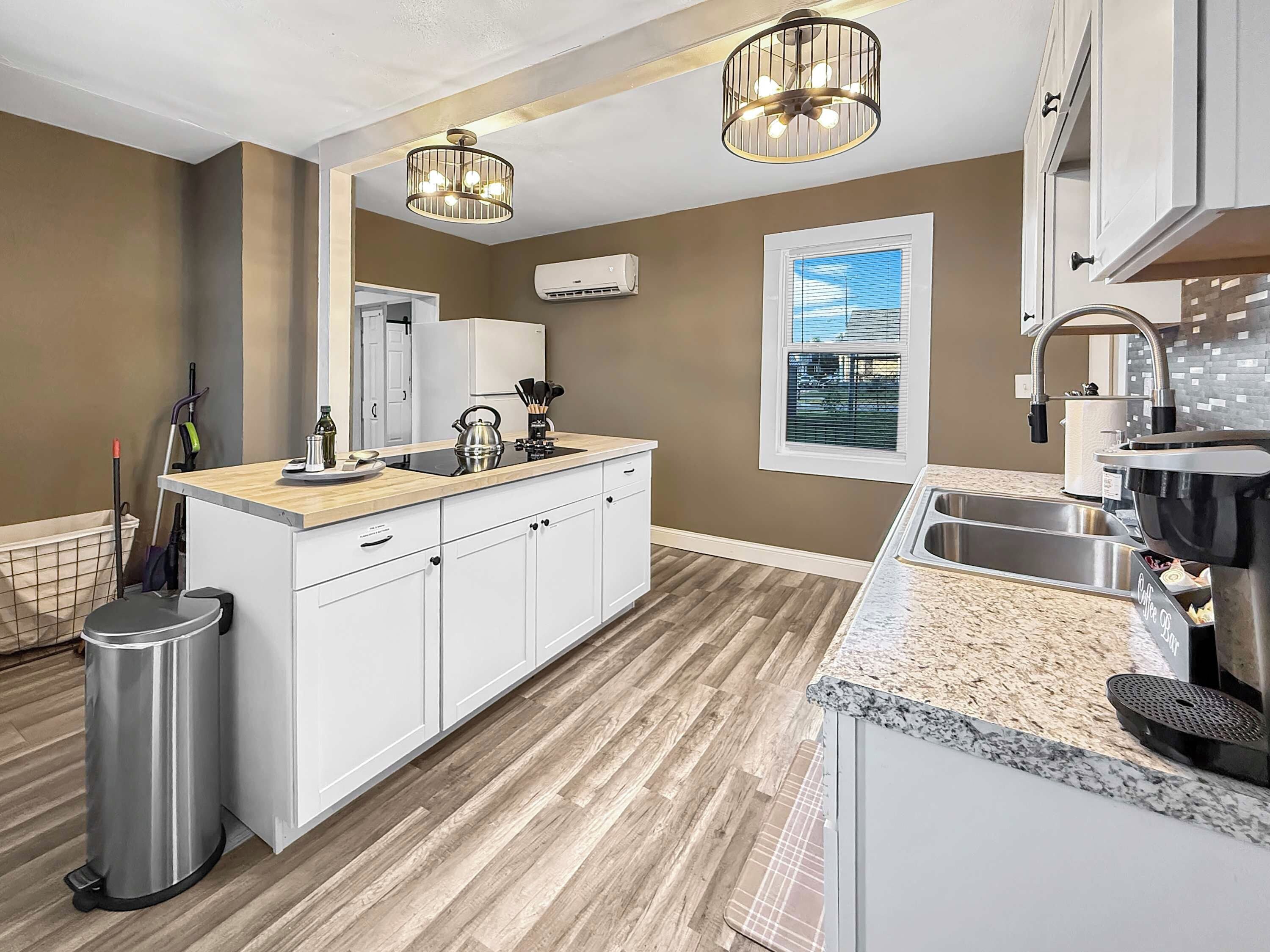 A modern kitchen with a central island, stainless steel appliances, and a window with blinds.