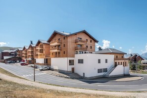 Un edificio de madera de varios pisos con balcones, fachada blanca y una carretera al frente.