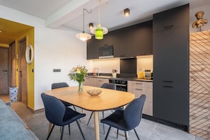Una cocina moderna con armarios oscuros, una mesa de comedor de madera y sillas azules.