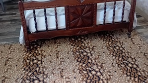 Un lit avec un cadre en bois et une couvre-lit à motifs, une petite table de chevet et une chaise.