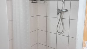 A shower area with a tiled wall, a showerhead, and a towel rack.