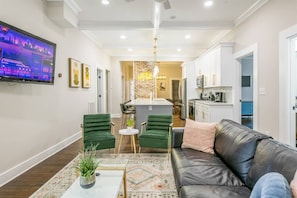 A modern living room with a leather sofa, green chairs, a coffee table, and a flat-screen TV. - Boho Home with driveway and lots of ensuite baths! (Atlanta)