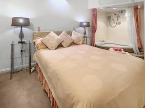 A hotel room with a bed, two bedside lamps, a bathroom with a bathtub, and a shower. - Apartment Sleeps 2 With Parking, Pets Welcome (Penrith)