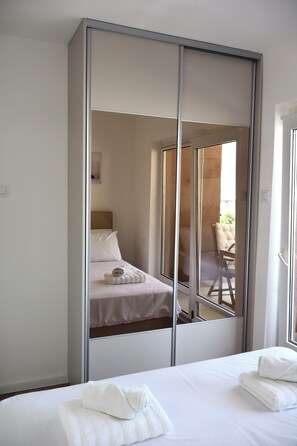 Quarto de hotel com cama, um espelho grande e vista para uma área de estar externa.