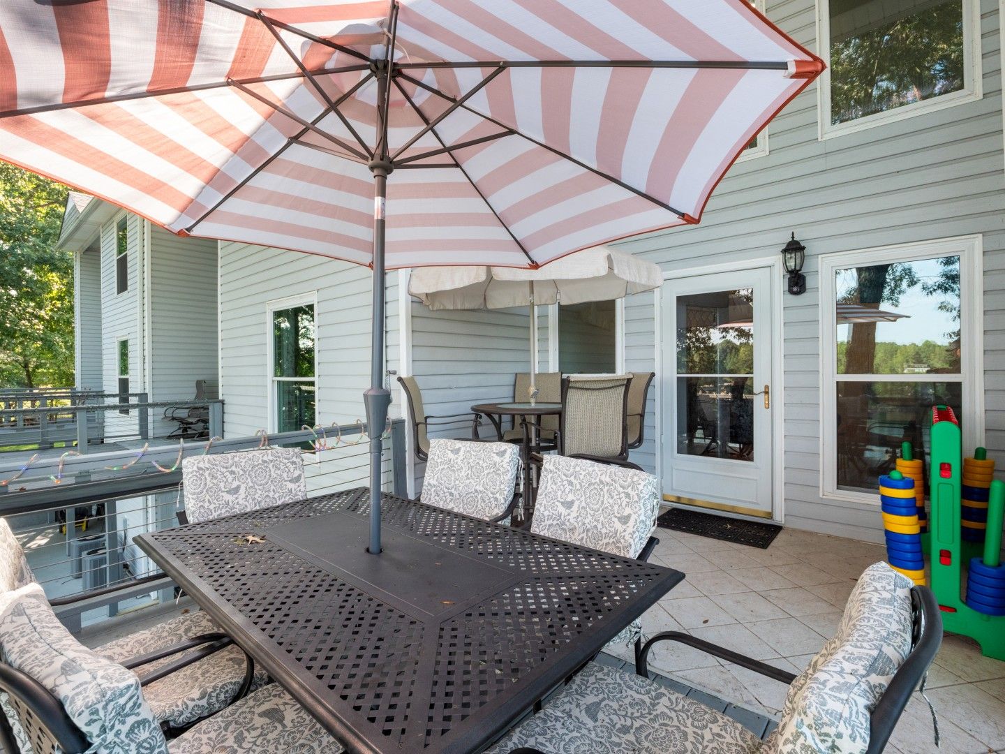 An outdoor patio with a table and chairs, an umbrella, and a play area with toys.