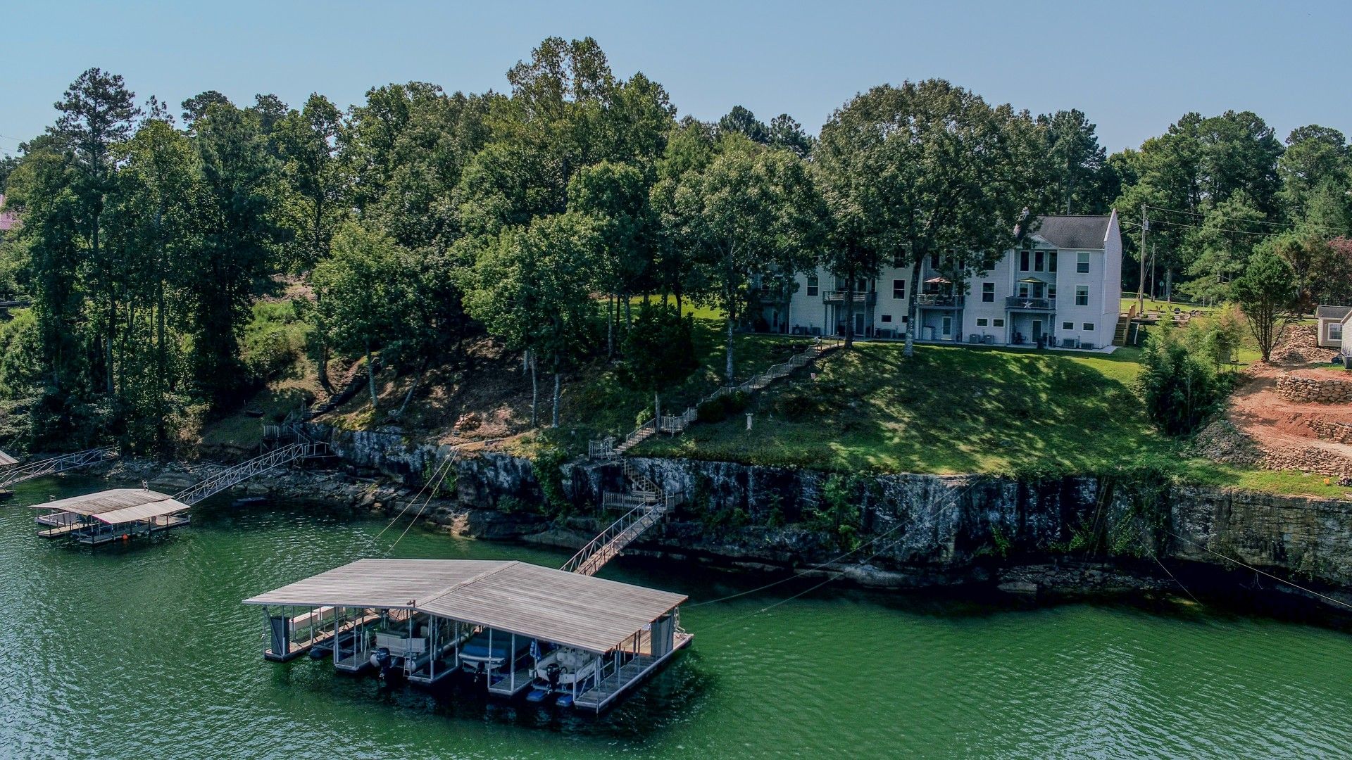 A lakeside property with a dock, a house, and a stone staircase leading to the house.