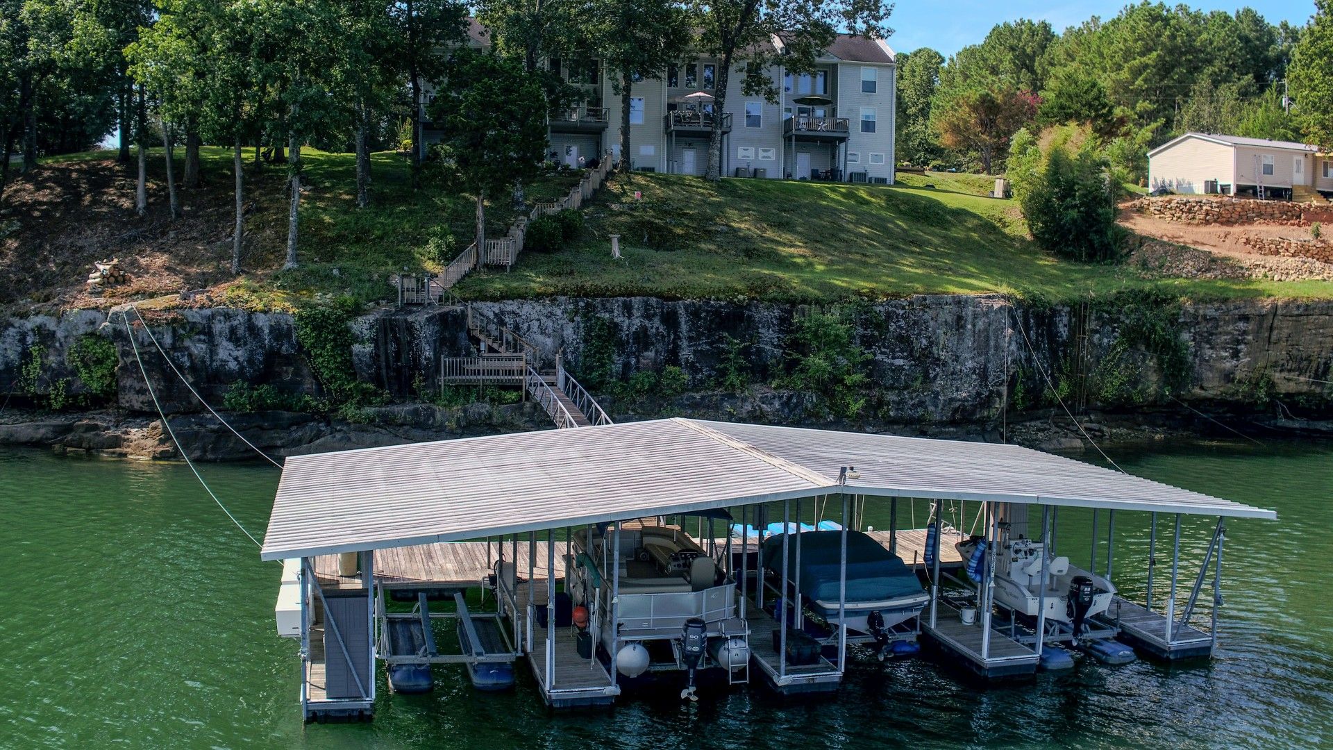 Ein an einem Steg festgemachtes Boot mit einer überdachten Deckfläche, ein kleines Boot und ein Haus im Hintergrund.