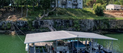 Ein an einem Steg festgemachtes Boot mit einer überdachten Deckfläche, ein kleines Boot und ein Haus im Hintergrund.