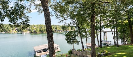 A lakeside property with a dock, a boat, and a bridge in the background.