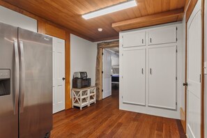A kitchen with a stainless steel refrigerator, wooden cabinets, and a microwave on a small table.