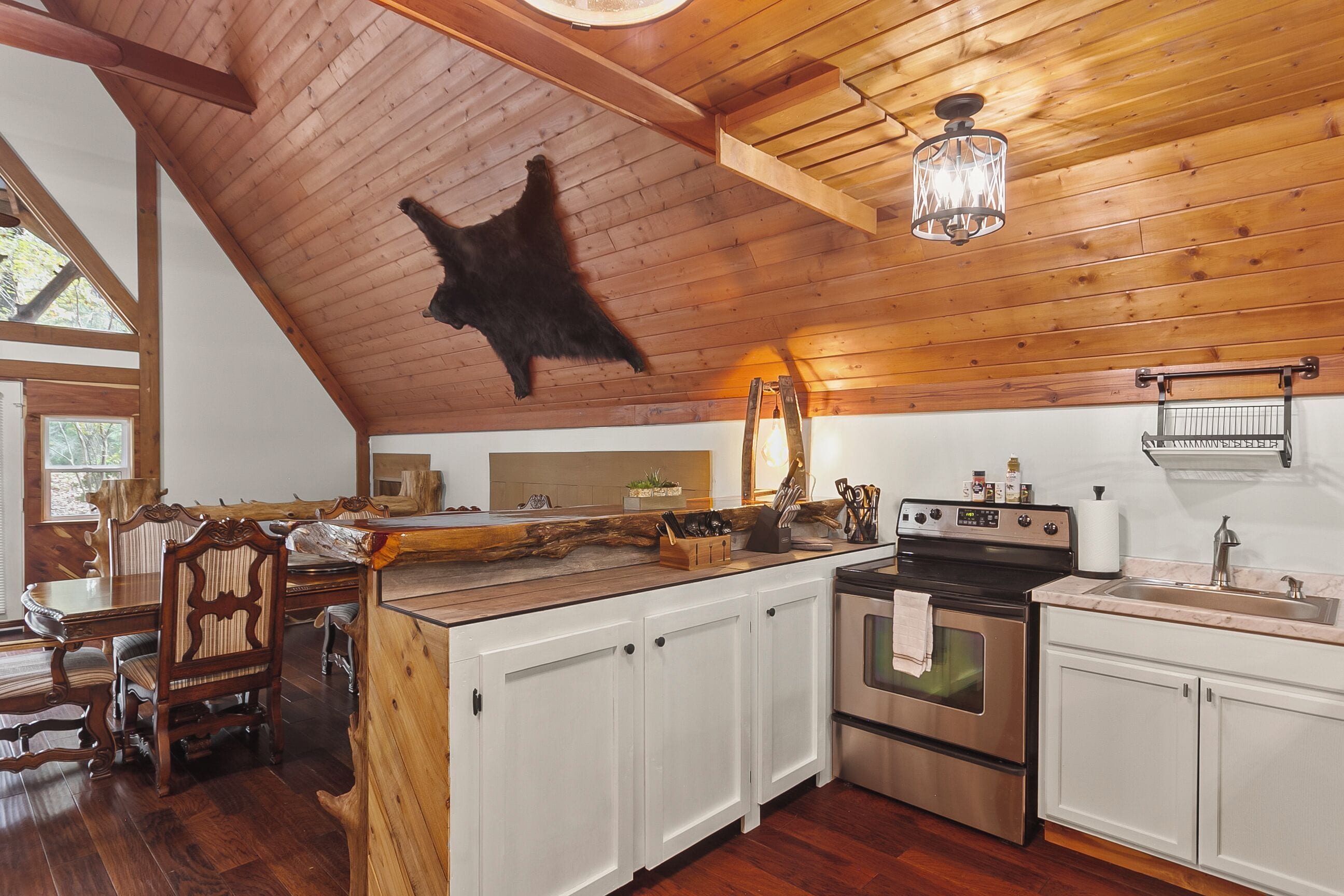 Une cuisine rustique avec des poutres en bois, un luminaire suspendu et un poêle.
