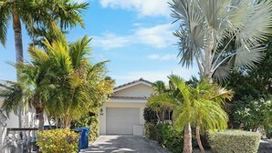 Ein Wohnhaus mit Garage, Palmen und einem gepflegten Garten.