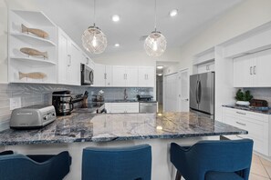 A modern kitchen with white cabinets, a granite countertop, and a stainless steel refrigerator. - Delightful 3-bedroom house in Key Colony Beach with Inch Beach Access & Dockage (Key Colony Beach)