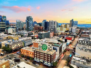 A cityscape with a prominent building featuring a green logo, surrounded by various other buildings and a clear sky. - The Penn Hotel - Queen Bed, AC & Gaslamp Nightlife! (San Diego)