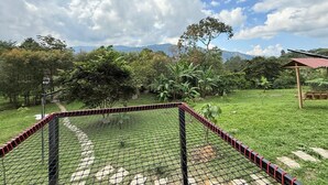 A fenced outdoor area with a paved path, surrounded by greenery and trees.
