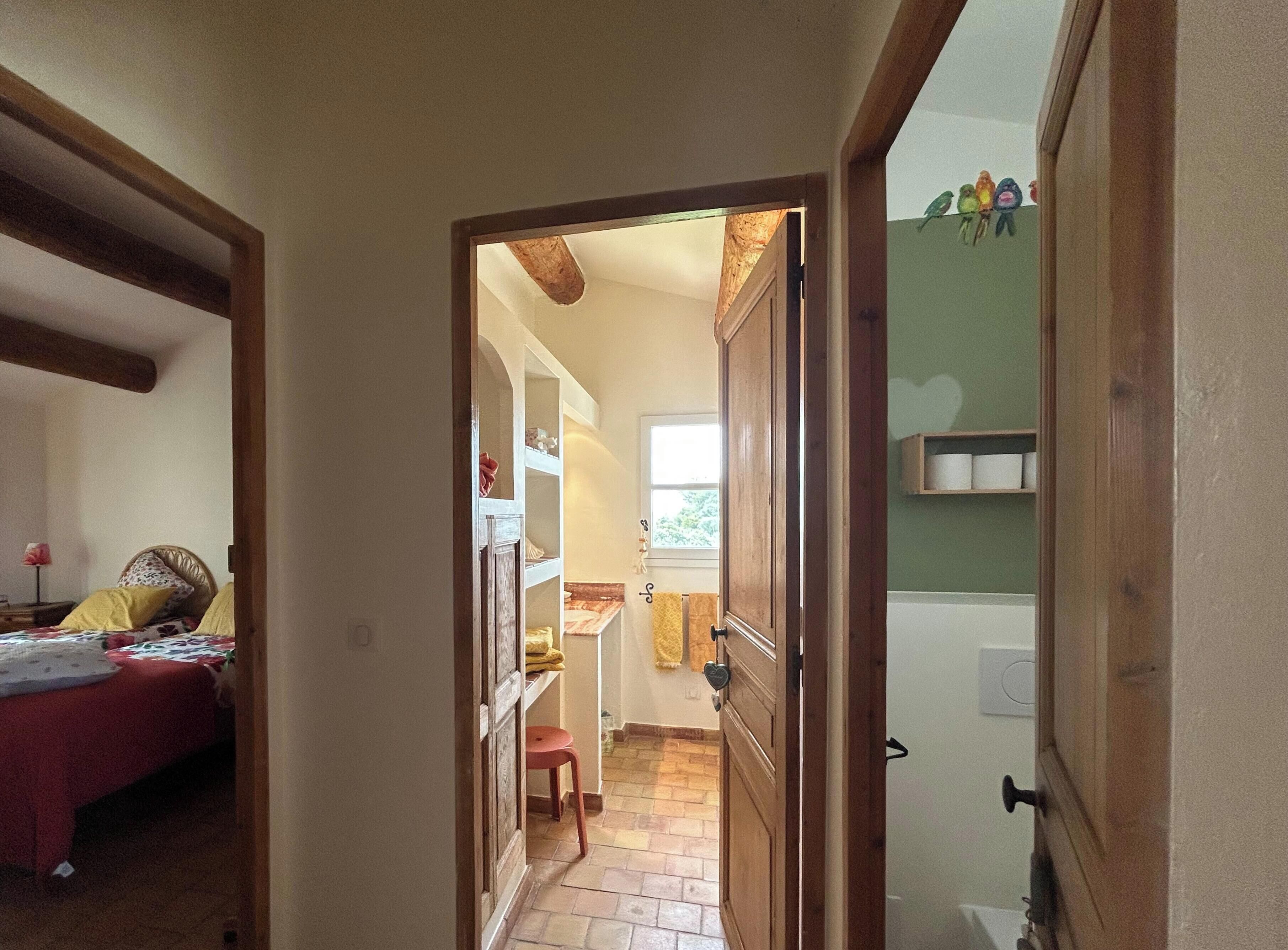 Un pasillo que conduce a un dormitorio con una cama y una silla roja.