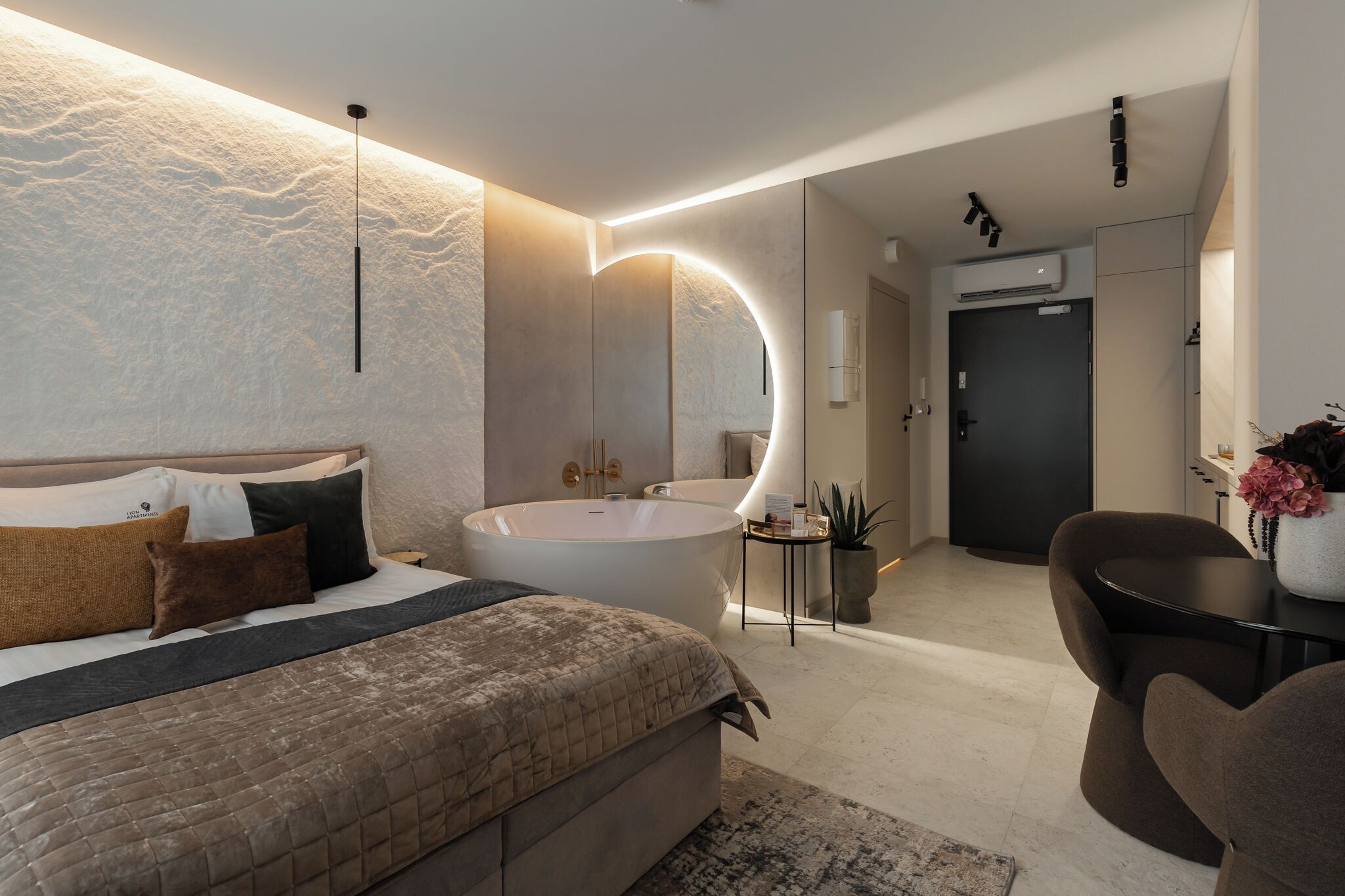 Ein modernes Schlafzimmer mit einem großen Bett, einer Badewanne und einem Schreibtisch mit Stuhl.