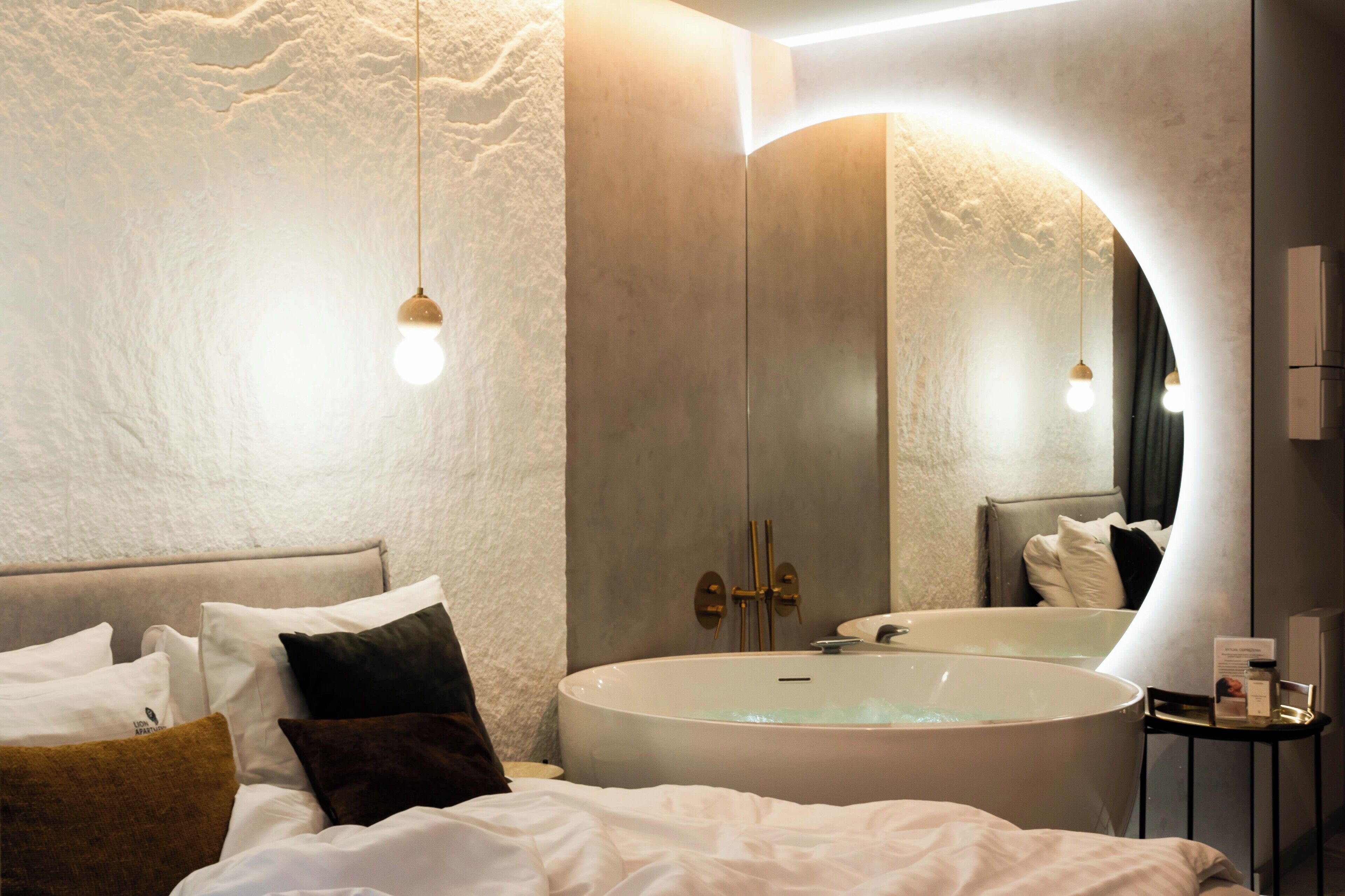 A modern bathroom with a freestanding bathtub, a large mirror, and a wall-mounted vanity.