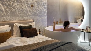 Une chambre dotée d ’un grand lit, d’une baignoire et d’un miroir qui reflète la pièce.