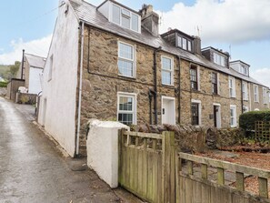 A stone-built terraced house with multiple windows and a wooden gate. - Ty Pen (Pwllheli)