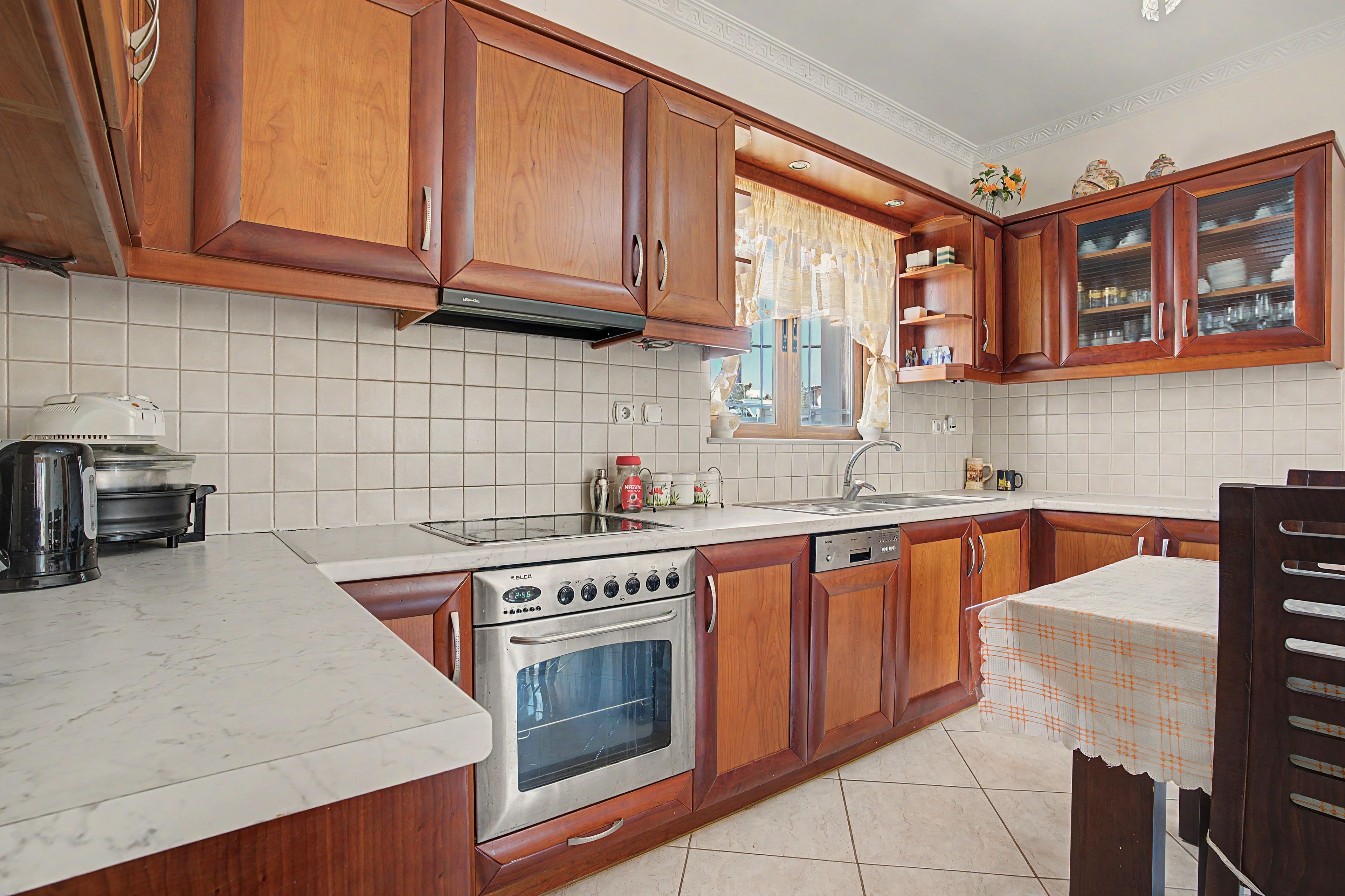 A kitchen with wooden cabinets, a stove, a sink, and a dishwasher.
