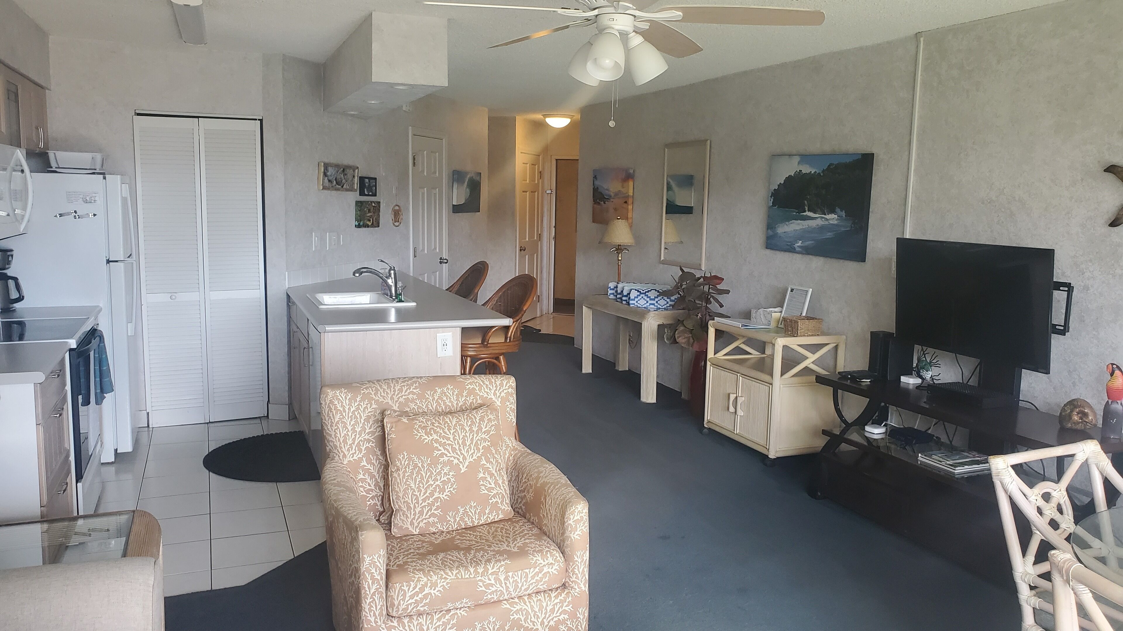 Un espacio habitable compacto con kitchenette, un sofá, zona de comedor y televisor.