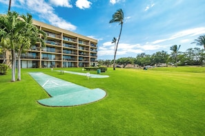 A hotel with a green lawn, a tennis court, and a multi-story building with balconies. - Beautiful Ocean View Condo Maui Sunset Resort Sleeps 4! (Kihei)