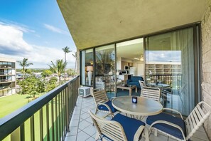 Ein Balkon mit Essbereich, inklusive Stühle und Tisch, mit Blick auf eine Wohngegend mit Häusern und Palmen.