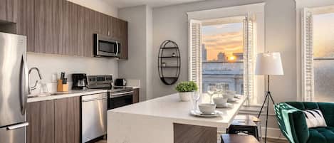 A modern kitchen with a central island, stainless steel appliances, and a city view through the window.