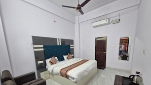 Una habitación de hotel con cama, sofá, una mesita, ventilador de techo y una puerta.